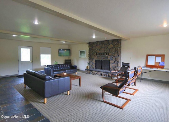 living area featuring stone finish floor, a fireplace, beamed ceiling, and baseboards