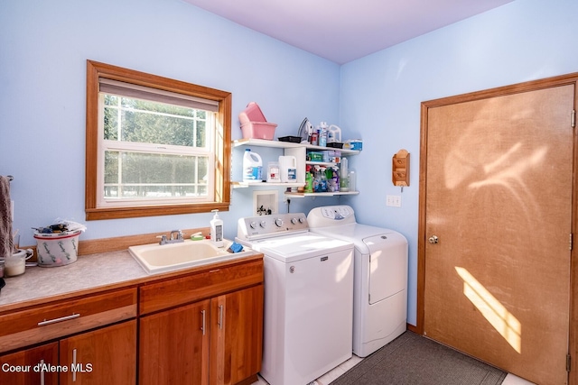 laundry room featuring sink, washer and clothes dryer, and cabinets