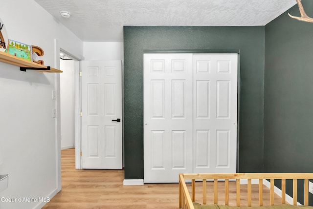 bedroom featuring light hardwood / wood-style flooring, a closet, and a textured ceiling