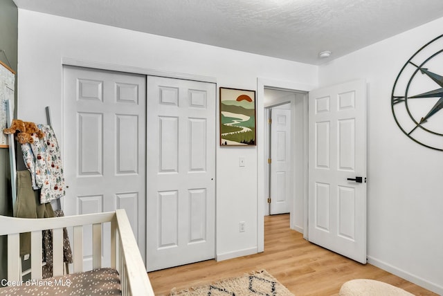 bedroom featuring a textured ceiling, a closet, and light hardwood / wood-style flooring