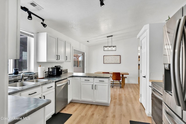 kitchen with appliances with stainless steel finishes, decorative light fixtures, kitchen peninsula, and white cabinets