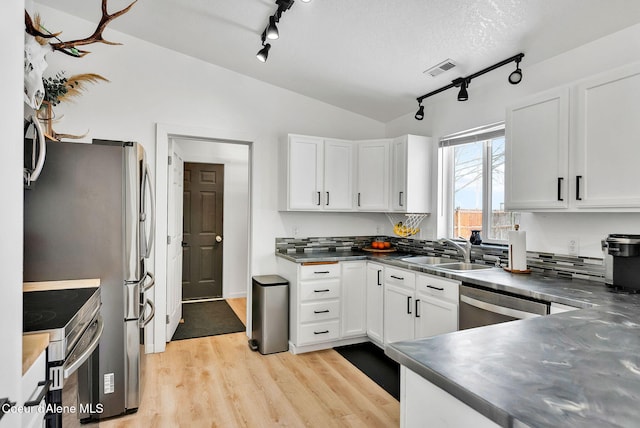 kitchen featuring sink, stainless steel appliances, white cabinets, and lofted ceiling