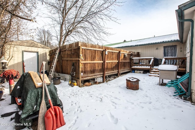 yard covered in snow with a deck and a storage shed