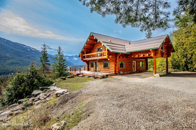 log home with log siding, driveway, and a deck with mountain view