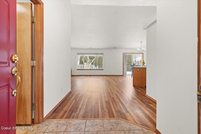 entrance foyer featuring a textured ceiling, baseboards, wood finished floors, and a notable chandelier