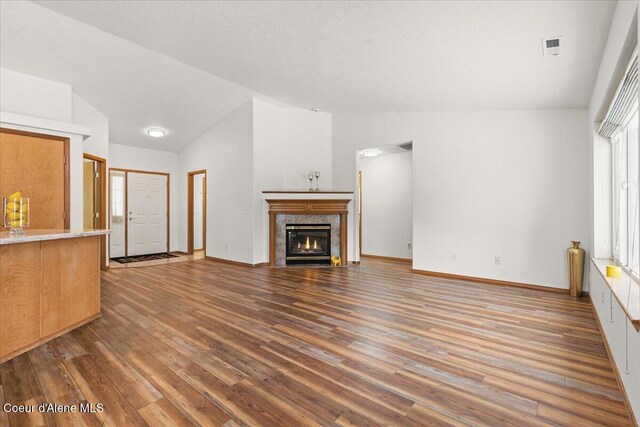 unfurnished living room featuring vaulted ceiling, a fireplace, wood finished floors, and baseboards