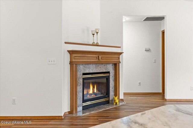 details with baseboards, visible vents, wood finished floors, and a high end fireplace