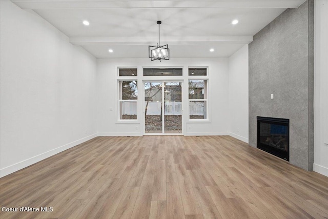 unfurnished living room with an inviting chandelier, light hardwood / wood-style flooring, a fireplace, and beam ceiling