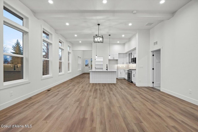 unfurnished living room with beam ceiling, light wood-type flooring, and a chandelier