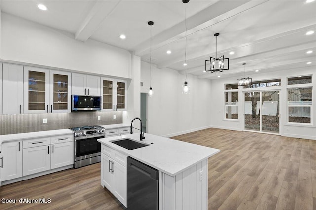 kitchen featuring sink, stainless steel appliances, white cabinets, and decorative light fixtures