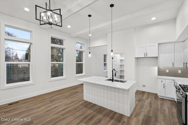 kitchen featuring a center island with sink, sink, pendant lighting, and white cabinets