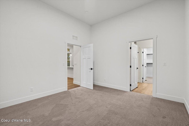 unfurnished bedroom with light carpet and a towering ceiling