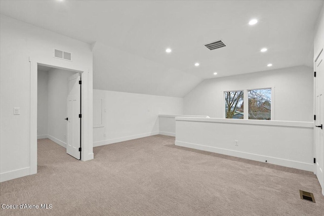 additional living space featuring light carpet and vaulted ceiling