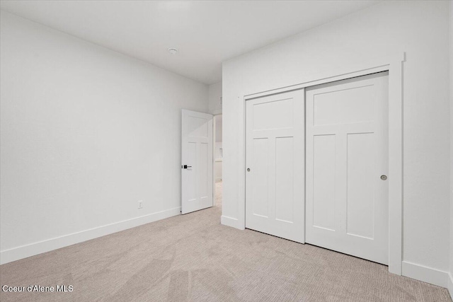 unfurnished bedroom with light carpet and a closet