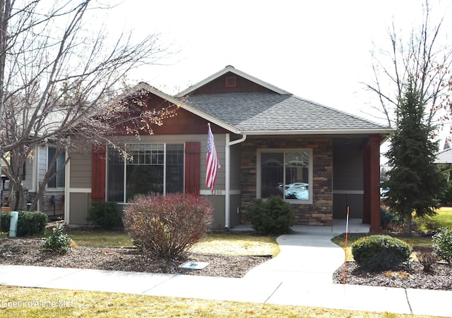 view of front of home with stone siding and roof with shingles