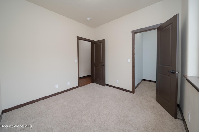 unfurnished bedroom with light carpet and baseboards