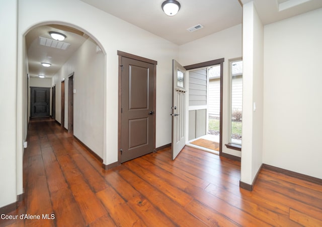 entryway with hardwood / wood-style flooring, arched walkways, visible vents, and baseboards