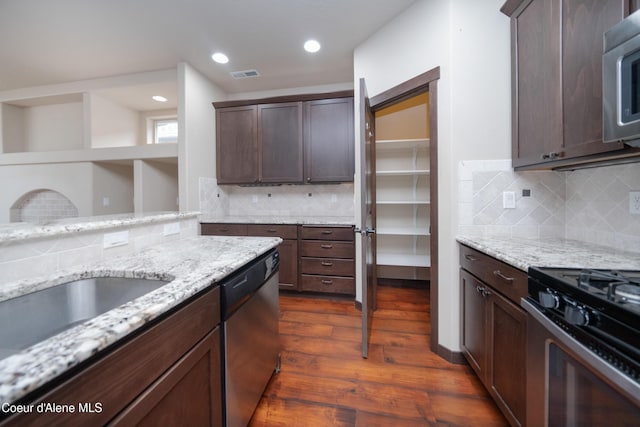 kitchen with dark wood finished floors, light stone counters, visible vents, and appliances with stainless steel finishes