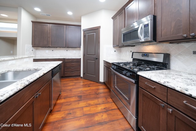 kitchen featuring visible vents, light stone counters, dark wood finished floors, appliances with stainless steel finishes, and dark brown cabinets