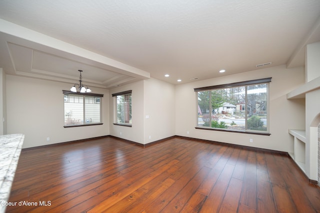 unfurnished living room with dark wood-style floors, baseboards, visible vents, a raised ceiling, and a chandelier