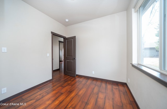 empty room featuring baseboards and dark wood-style flooring