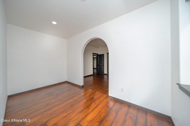 unfurnished room with hardwood / wood-style floors, recessed lighting, baseboards, and arched walkways