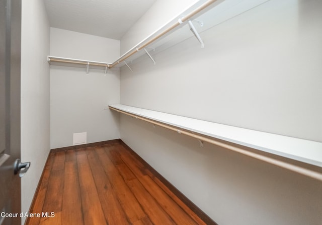 walk in closet with dark wood-type flooring