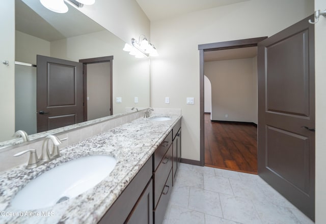 full bath featuring a sink, baseboards, and double vanity