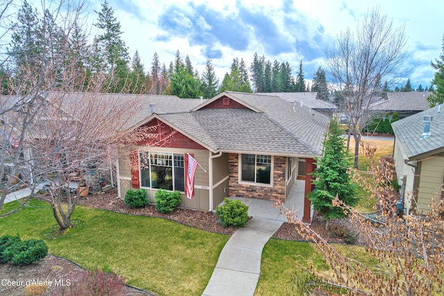 single story home featuring a front yard, stone siding, and roof with shingles