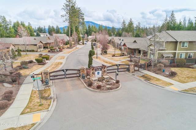 view of road featuring sidewalks, a gate, curbs, and a residential view