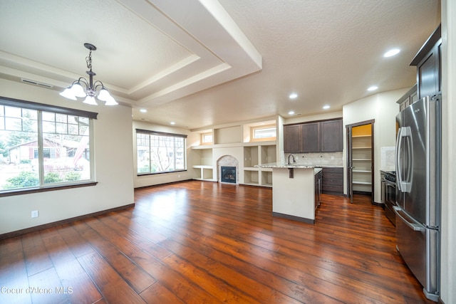 kitchen featuring dark wood finished floors, a fireplace, stainless steel appliances, a kitchen breakfast bar, and open floor plan