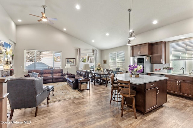 kitchen featuring light wood-style flooring, a center island, smart refrigerator, pendant lighting, and a sink