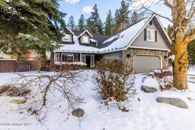 view of front of home featuring stone siding, an attached garage, and fence