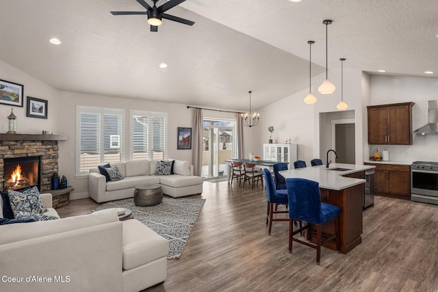 living area featuring vaulted ceiling, dark wood-type flooring, a textured ceiling, and a fireplace