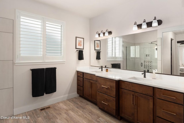 bathroom featuring a stall shower, visible vents, a sink, and wood finished floors