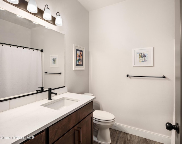 full bathroom with wood finished floors, vanity, toilet, and baseboards