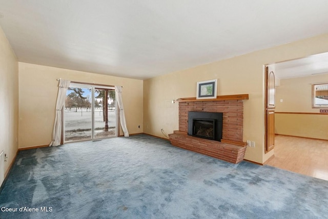 unfurnished living room featuring a brick fireplace, carpet, and baseboards