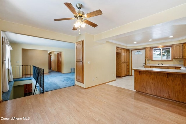 kitchen featuring brown cabinets, light countertops, light wood-type flooring, a peninsula, and baseboards