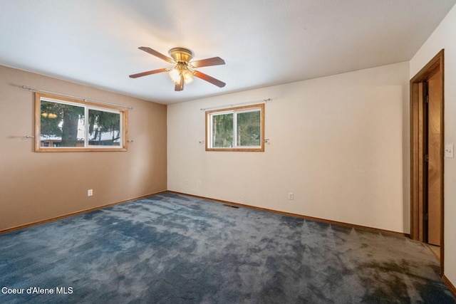 unfurnished room with ceiling fan, dark carpet, and baseboards