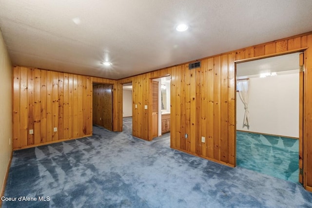 interior space with wooden walls, visible vents, and dark colored carpet