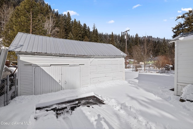 snow covered garage with fence