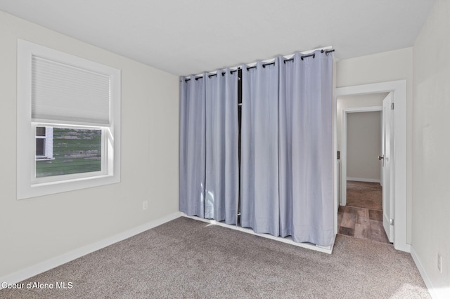 empty room featuring baseboards and carpet flooring