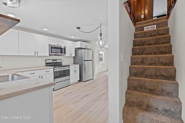 kitchen with white cabinetry, appliances with stainless steel finishes, light countertops, and a sink