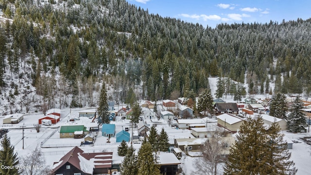 snowy aerial view featuring a residential view and a wooded view