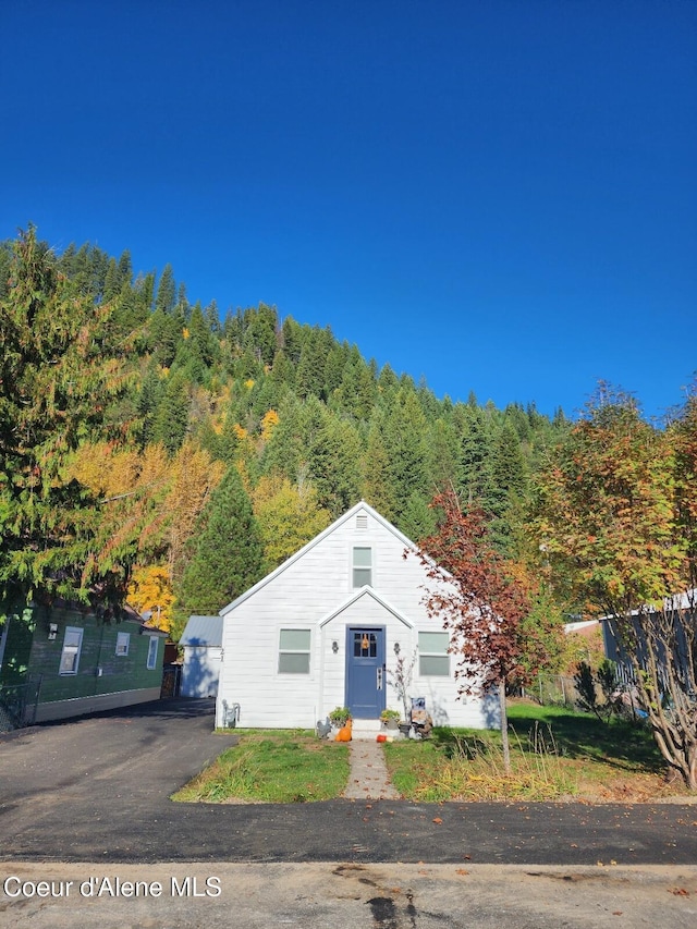 bungalow-style home with a forest view and fence