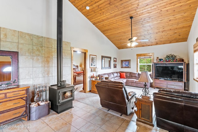 living area featuring ceiling fan, high vaulted ceiling, light tile patterned flooring, wood ceiling, and a wood stove