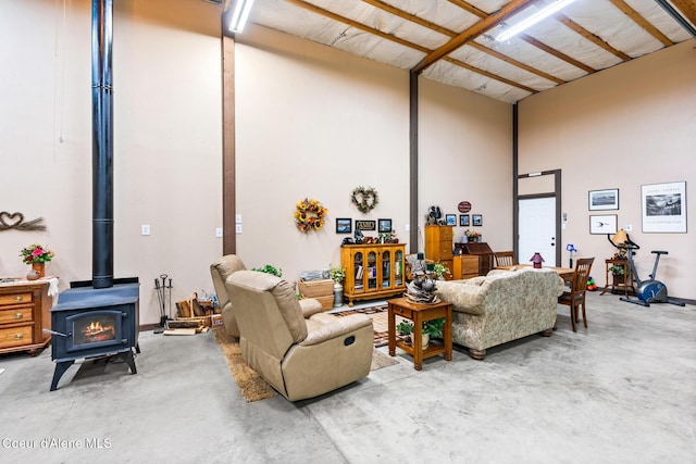 living area featuring a wood stove, concrete floors, and a high ceiling