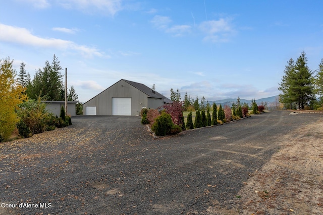 view of side of home featuring a detached garage, a mountain view, and an outbuilding