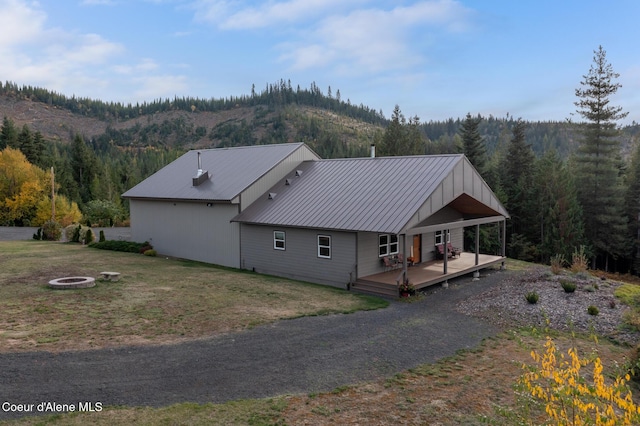 view of side of home featuring metal roof, a forest view, an outdoor fire pit, and a deck with mountain view