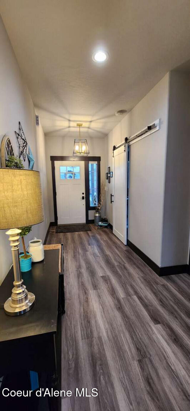 interior space featuring a barn door, baseboards, and dark wood-style flooring